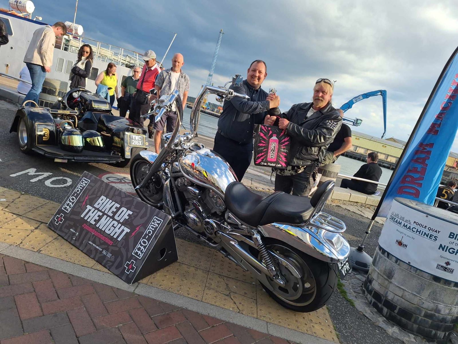 Bike night winner standing next to a judge with his winning motorbike 